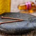 Two acupuncture needles on a black stone