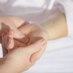 A massage therapist massages a client's hand