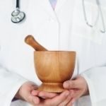 A naturopathic physician holds a mortar and pestal